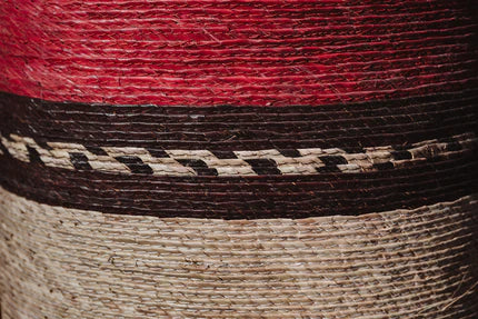 Canasto redondo artesanal, cesto tejido en tonos rojos, cafés de palma